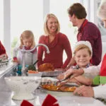 Family around the kitchen while grandmother cuts holiday food